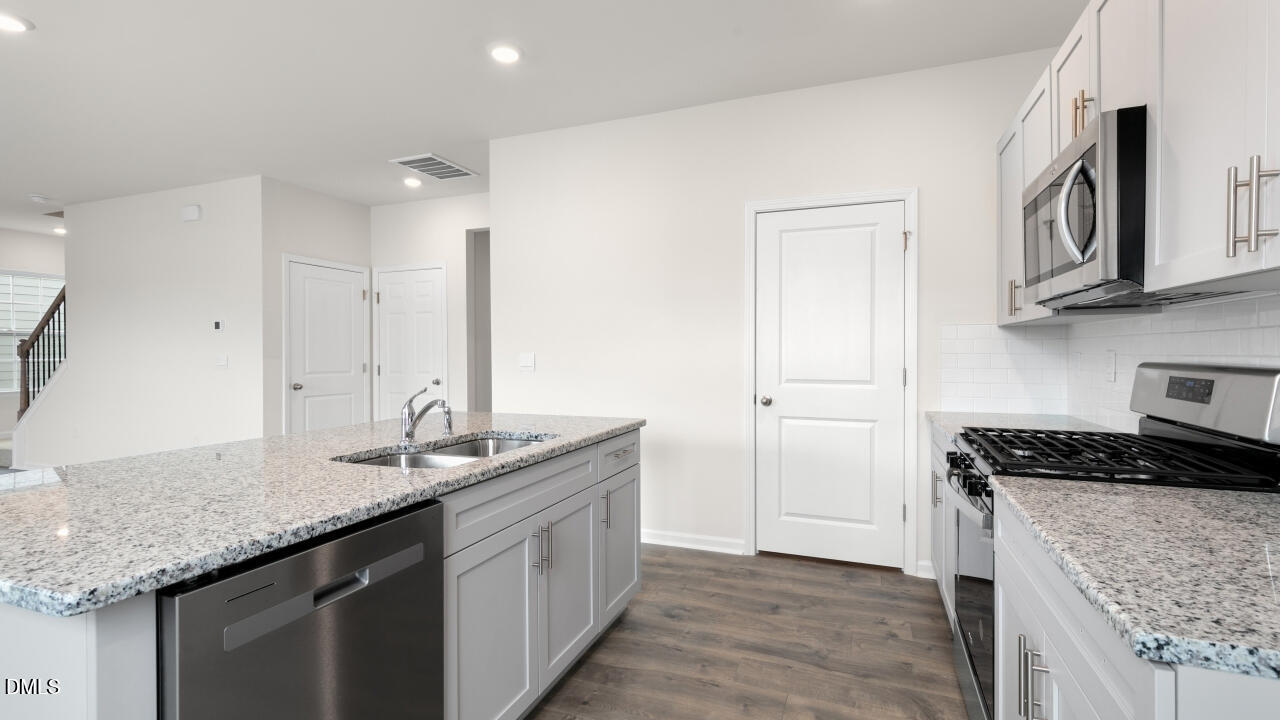 1253 Pavo Path Wendell, NC 27591 - Photo 9 of 41 a kitchen with stainless steel appliances granite countertop a sink stove and cabinets