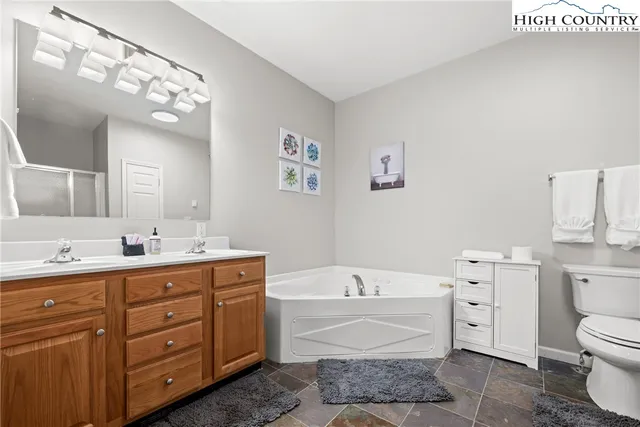 a bathroom with a granite countertop toilet a sink a mirror bathtub and vanity