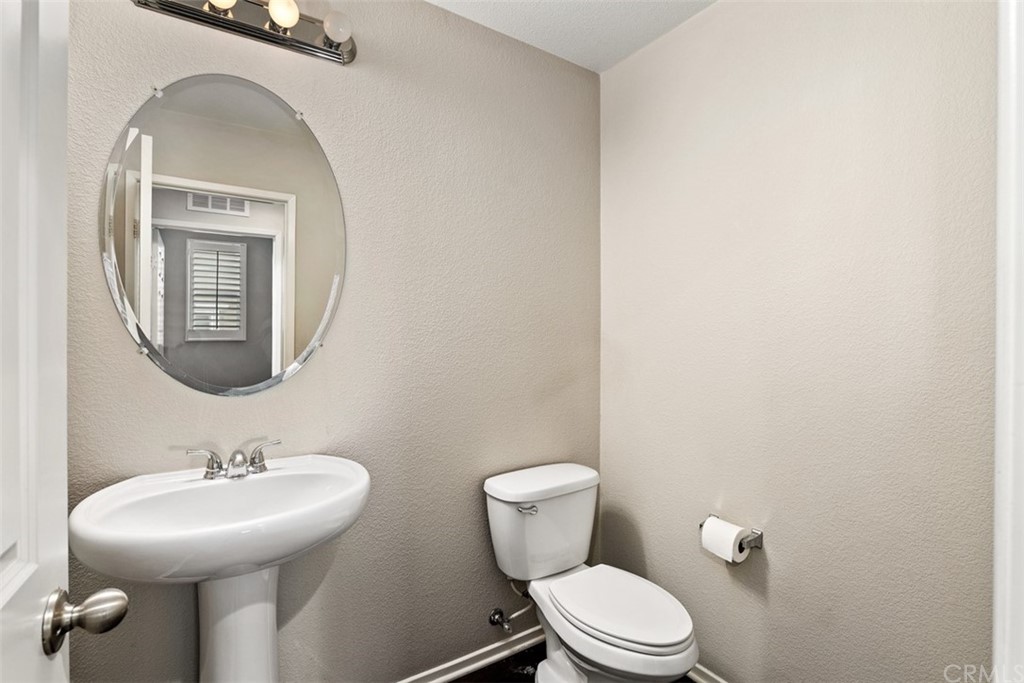 46945 Peach Tree Street Temecula, CA 92592 - Photo 15 of 32 a bathroom with a toilet a sink and mirror