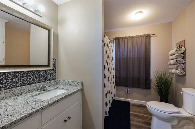a bathroom with a granite countertop sink a toilet a mirror and shower