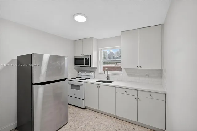 a kitchen with stainless steel appliances granite countertop a refrigerator a sink a stove a microwave a sink and white cabinets