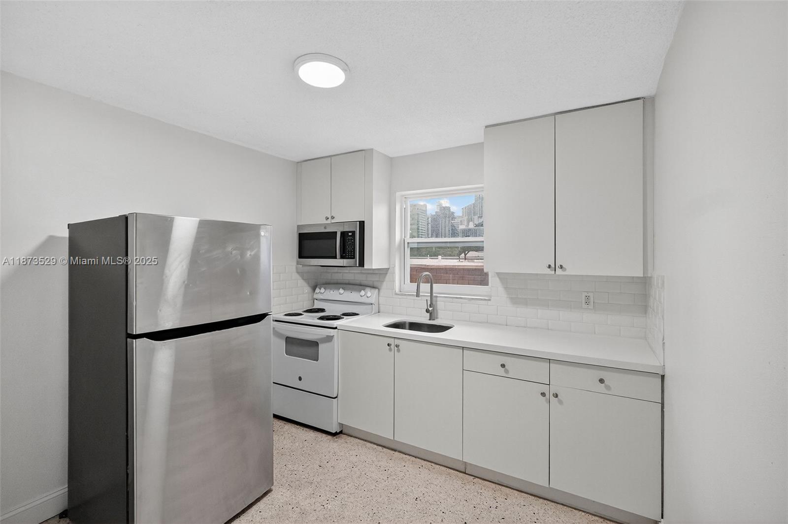 a kitchen with stainless steel appliances granite countertop a refrigerator a sink a stove a microwave a sink and white cabinets