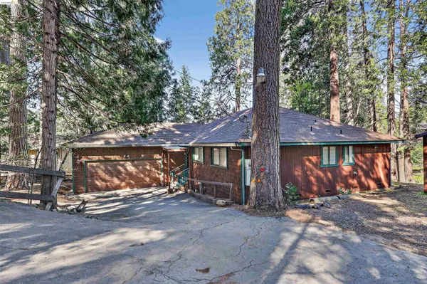 a view of a wooden house with large trees and wooden fence