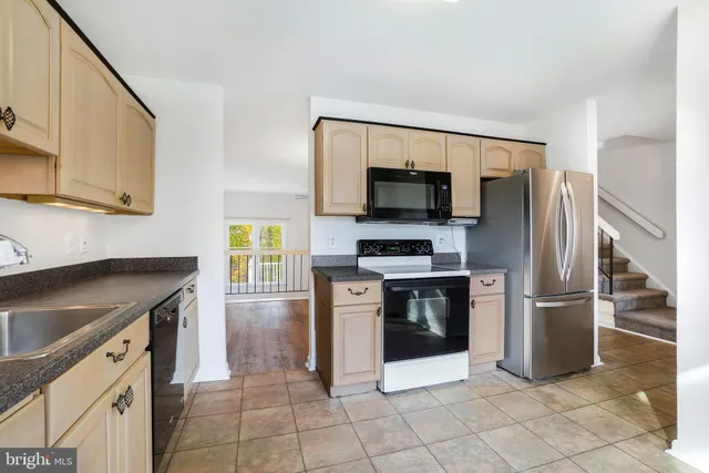 a kitchen with granite countertop a refrigerator and a stove top oven