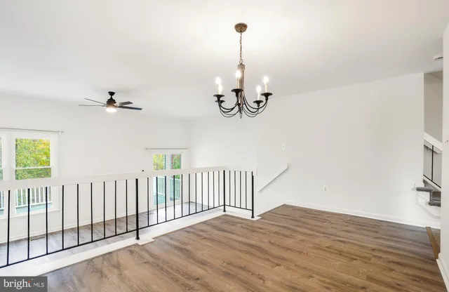 a view of a room with wooden floor chandelier fan and windows