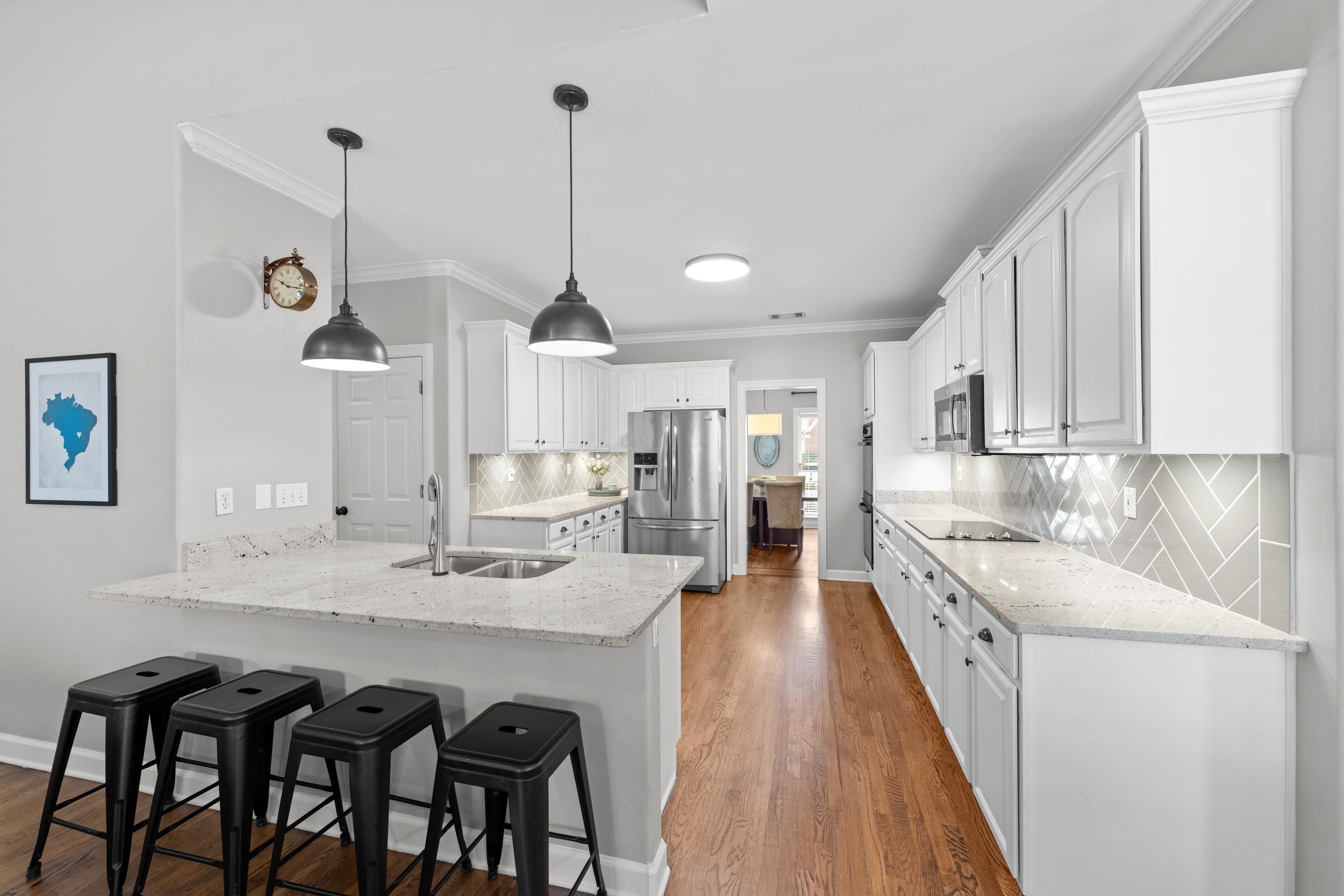 a kitchen with stainless steel appliances kitchen island granite countertop a sink a stove and white cabinets