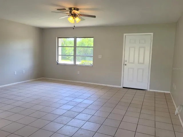 an empty room with windows and chandelier fan