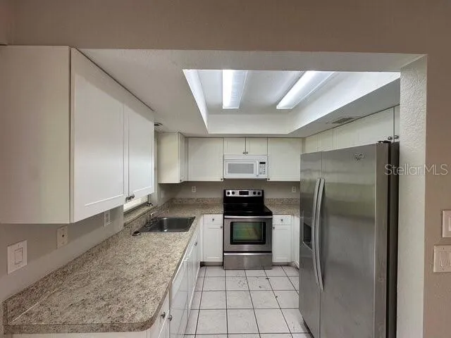 a kitchen with a refrigerator sink and cabinets