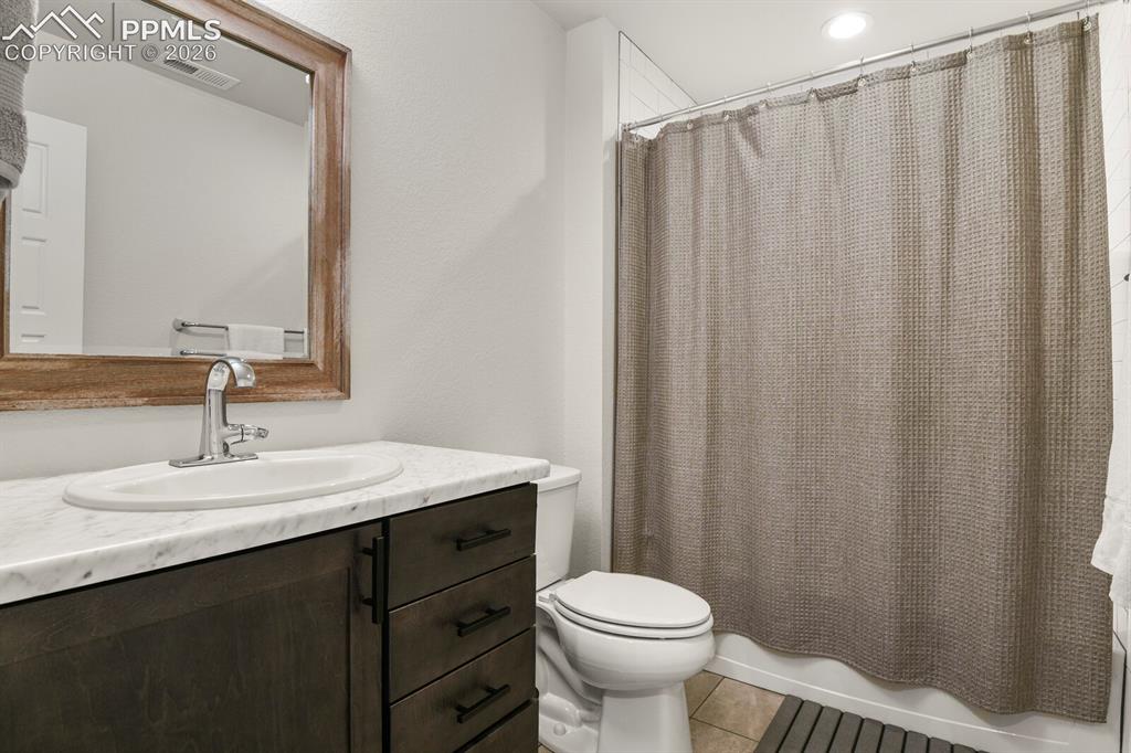 11314 Modern Meadow Loop Colorado Springs, CO 80921 - Photo 24 of 30 a bathroom with a sink a toilet a mirror and shower curtain