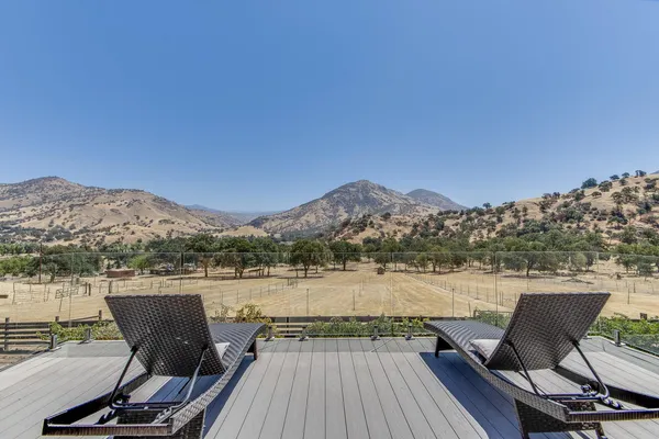 a view of a chairs and table on wooden deck with lake view