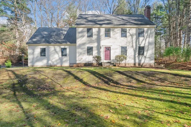 a view of a white building with a big yard and large trees