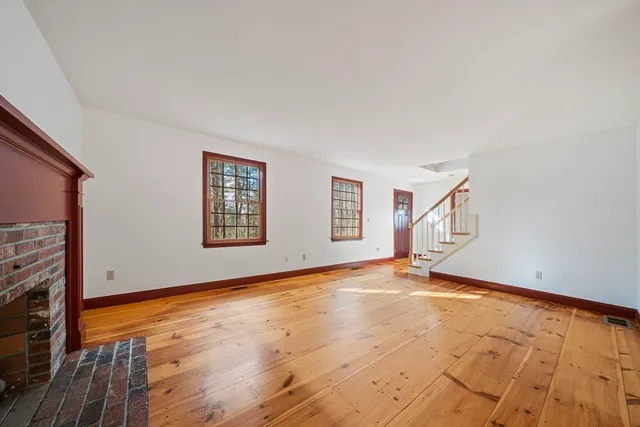 a view of an empty room with window and wooden floor