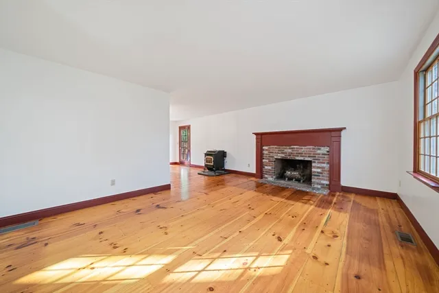 a view of empty room with wooden floor and fireplace