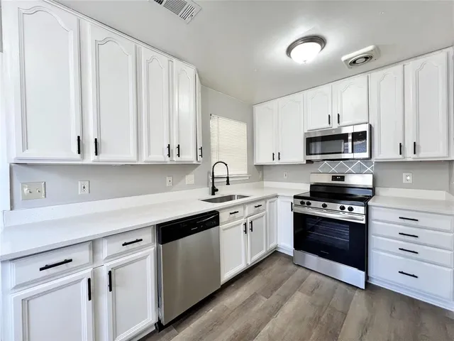 a kitchen with granite countertop white cabinets and stainless steel appliances