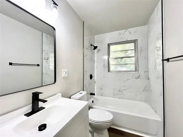 a bathroom with a bathtub shower sink vanity mirror and toilet