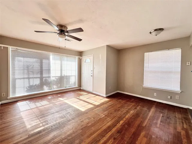 a view of an empty room with a window and wooden floor