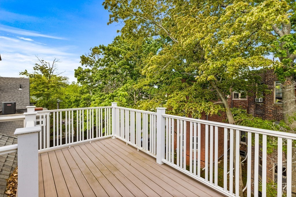 87 Coolidge Street, Unit 2 Brookline, MA 02446 - Photo 20 of 34 a balcony with wooden floor and trees in the background