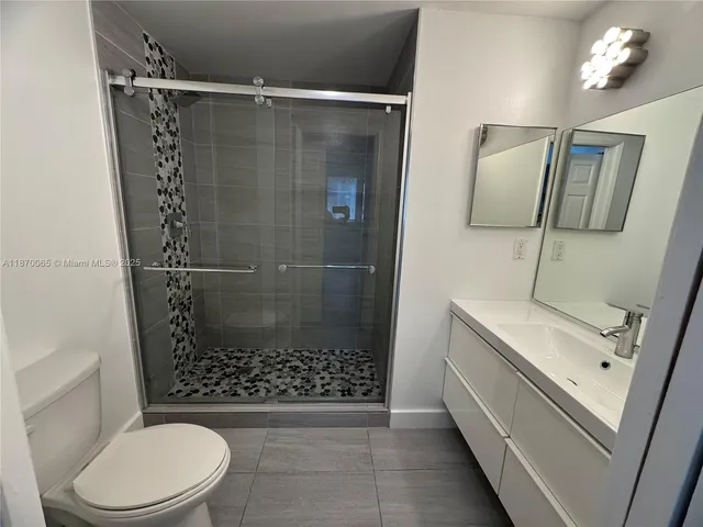 a bathroom with a double vanity sink a toilet a mirror and shower