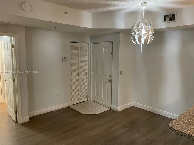 an empty room with wooden floor chandelier and windows