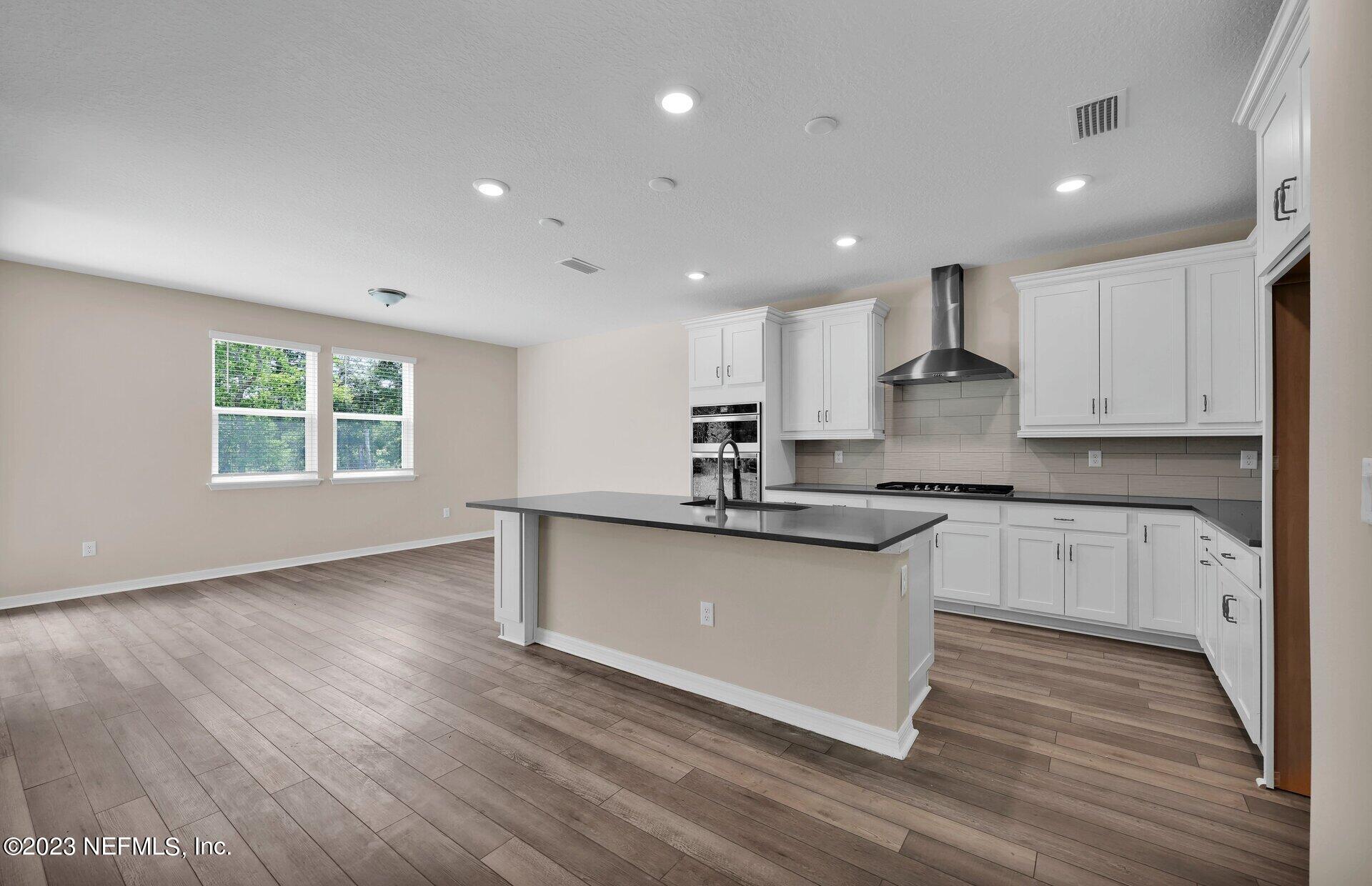 338 Red Barn Road St. Augustine, FL 32092 - Photo 14 of 34 a kitchen with stainless steel appliances granite countertop a sink a stove a refrigerator and white cabinets with wooden floor