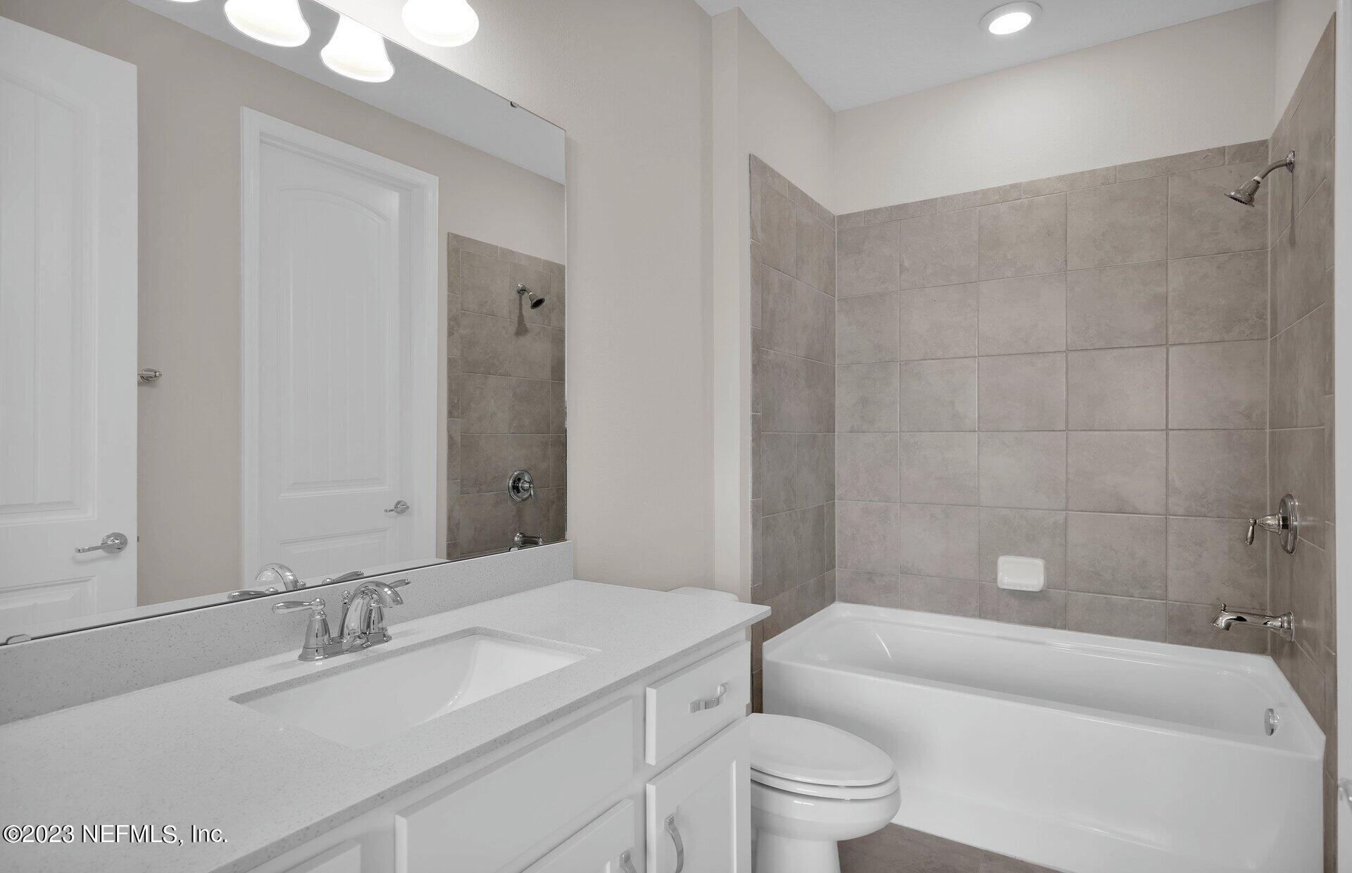338 Red Barn Road St. Augustine, FL 32092 - Photo 27 of 34 a bathroom with a granite countertop bathtub shower sink mirror vanity and toilet