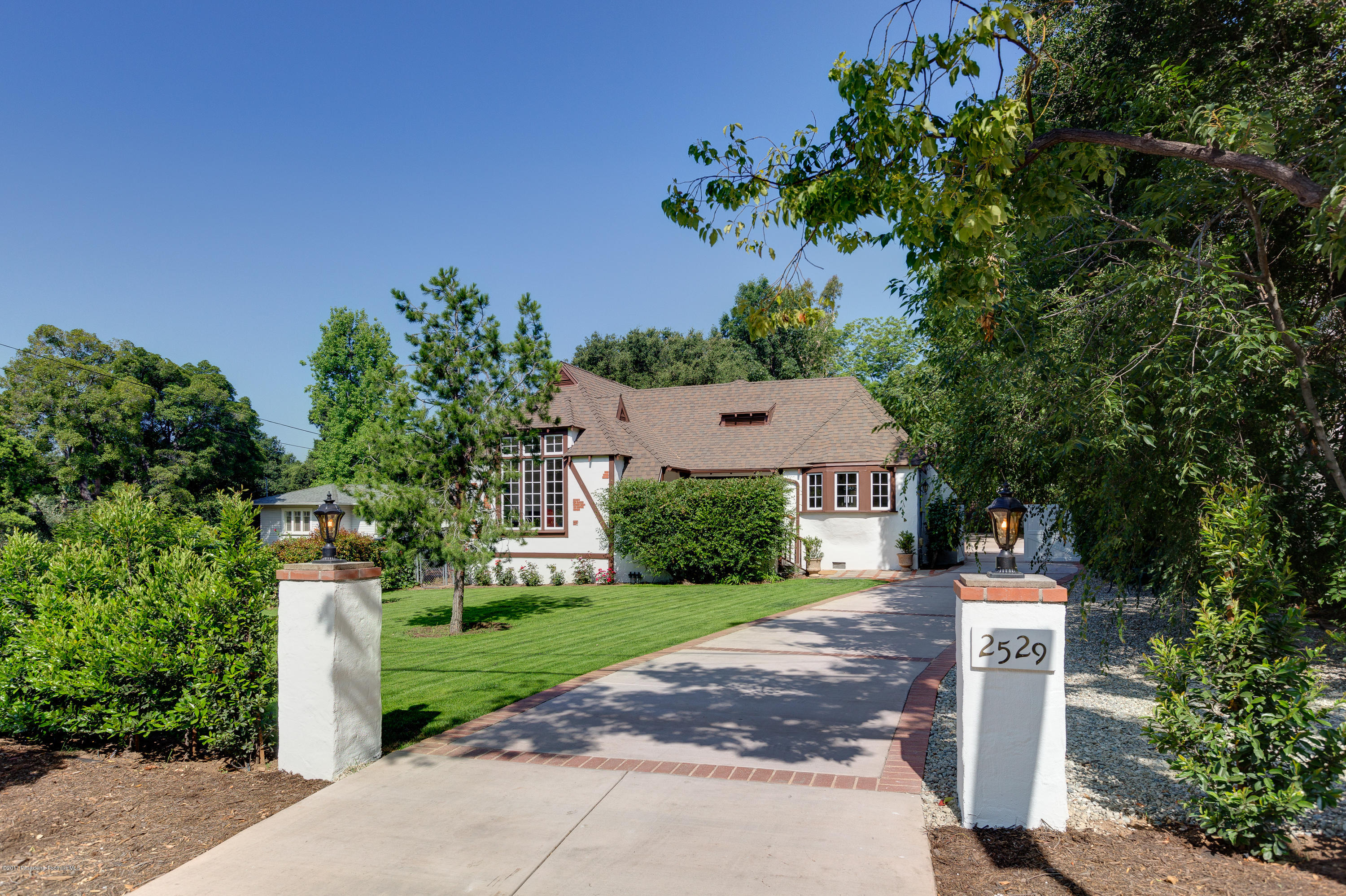 a front view of a house with a garden and tree