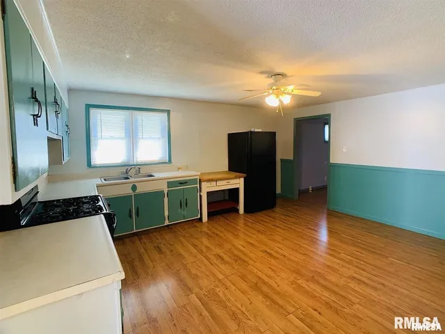a kitchen with kitchen island a sink wooden floor and stainless steel appliances