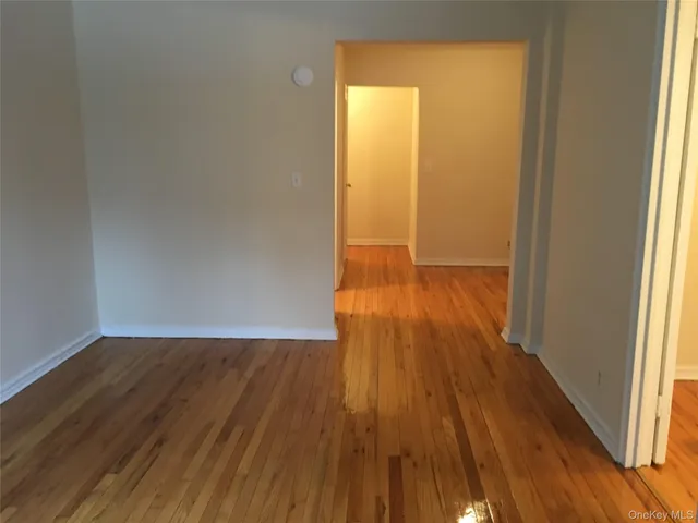 a view of wooden floor in an empty room with a window