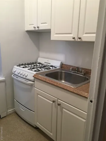 a kitchen with granite countertop white cabinets and a white stove