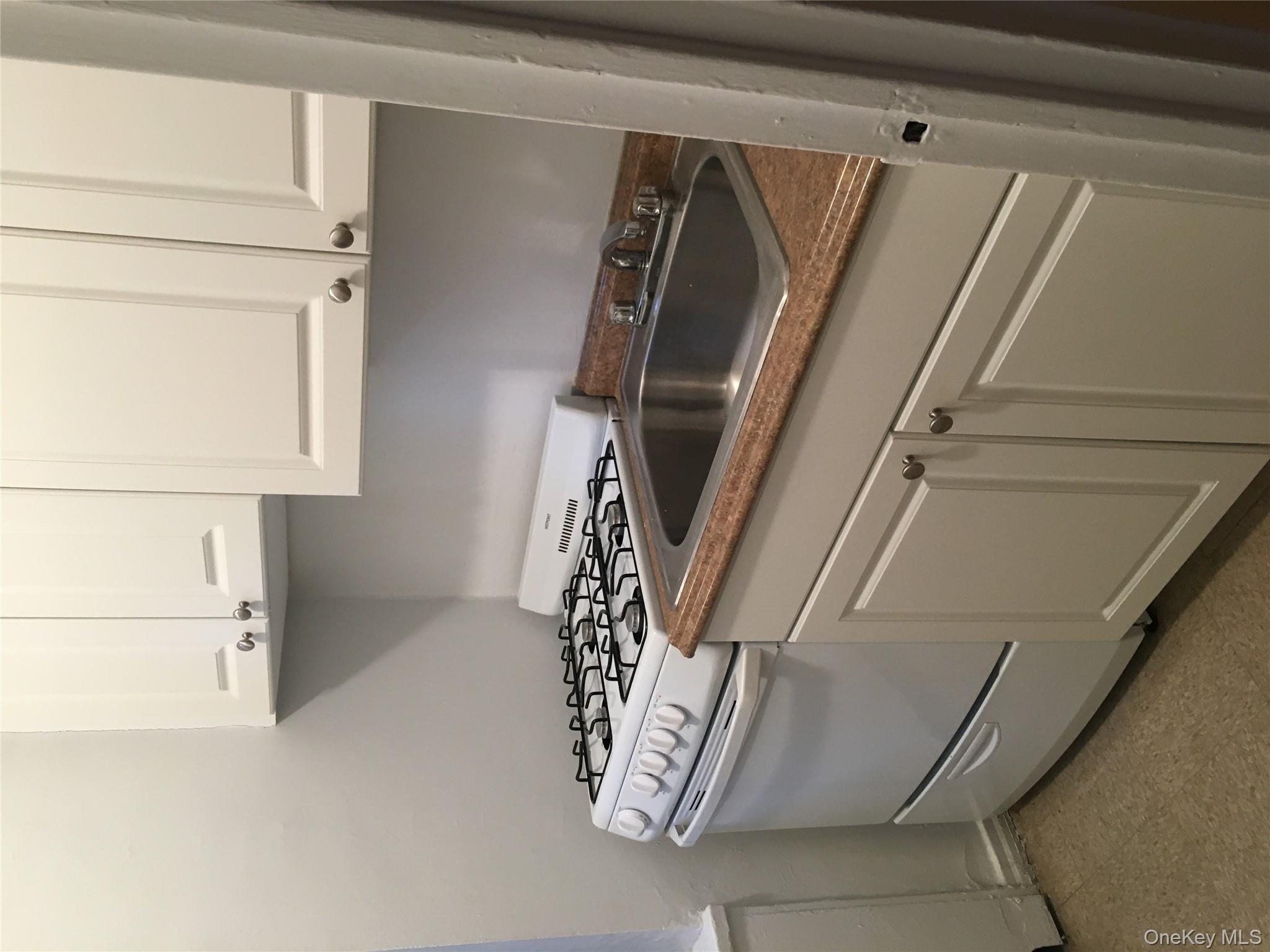 23 Schenck Avenue, Unit 1BD Great Neck, NY 11021 - Photo 5 of 14 a kitchen with granite countertop white cabinets and a white stove