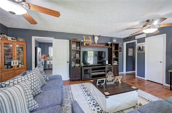 a kitchen with stainless steel appliances granite countertop a refrigerator a sink a stove and white cabinets with wooden floor