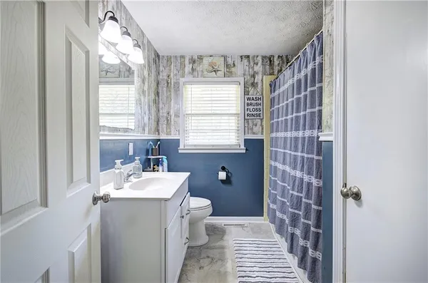 a view of a hallway with wooden floor a fireplace and a kitchen