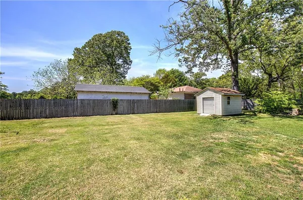 a tall yellow house with a big yard and large trees