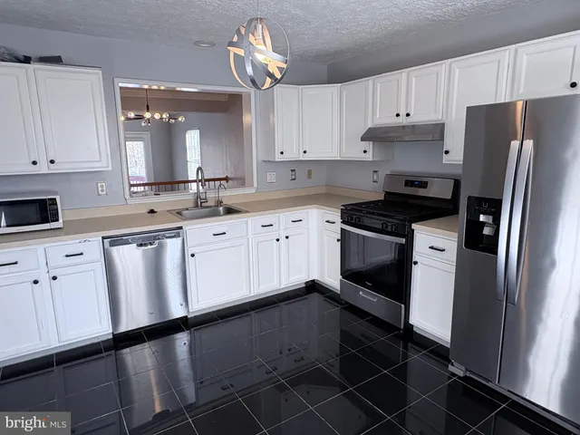 a view of a hallway with wooden floor and a chandelier
