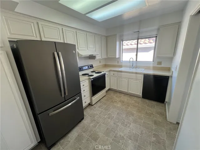 a kitchen with stainless steel appliances granite countertop a refrigerator a sink a stove and a refrigerator
