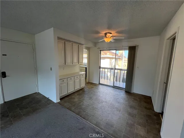 an empty room with windows and a kitchen view