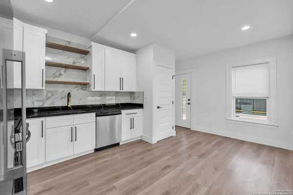 a kitchen with kitchen island a sink a refrigerator and white cabinets