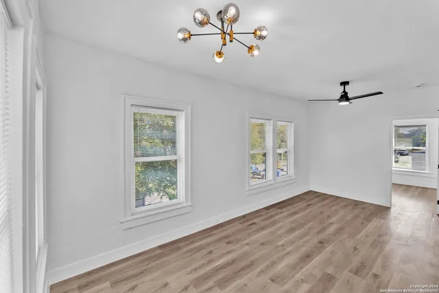 a view of an empty room with a window and wooden floor