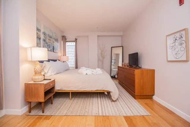 a spacious bedroom with a bed and wooden floor