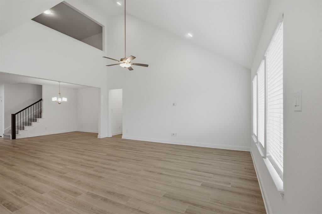 2911 Hanscom Street Forney, TX 75126 - Photo 19 of 40 Spacious living area featuring high vaulted ceilings, light wood-finish flooring, and multiple windows with blinds
