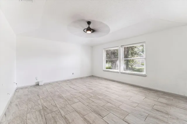 an empty room with a window and a ceiling fan