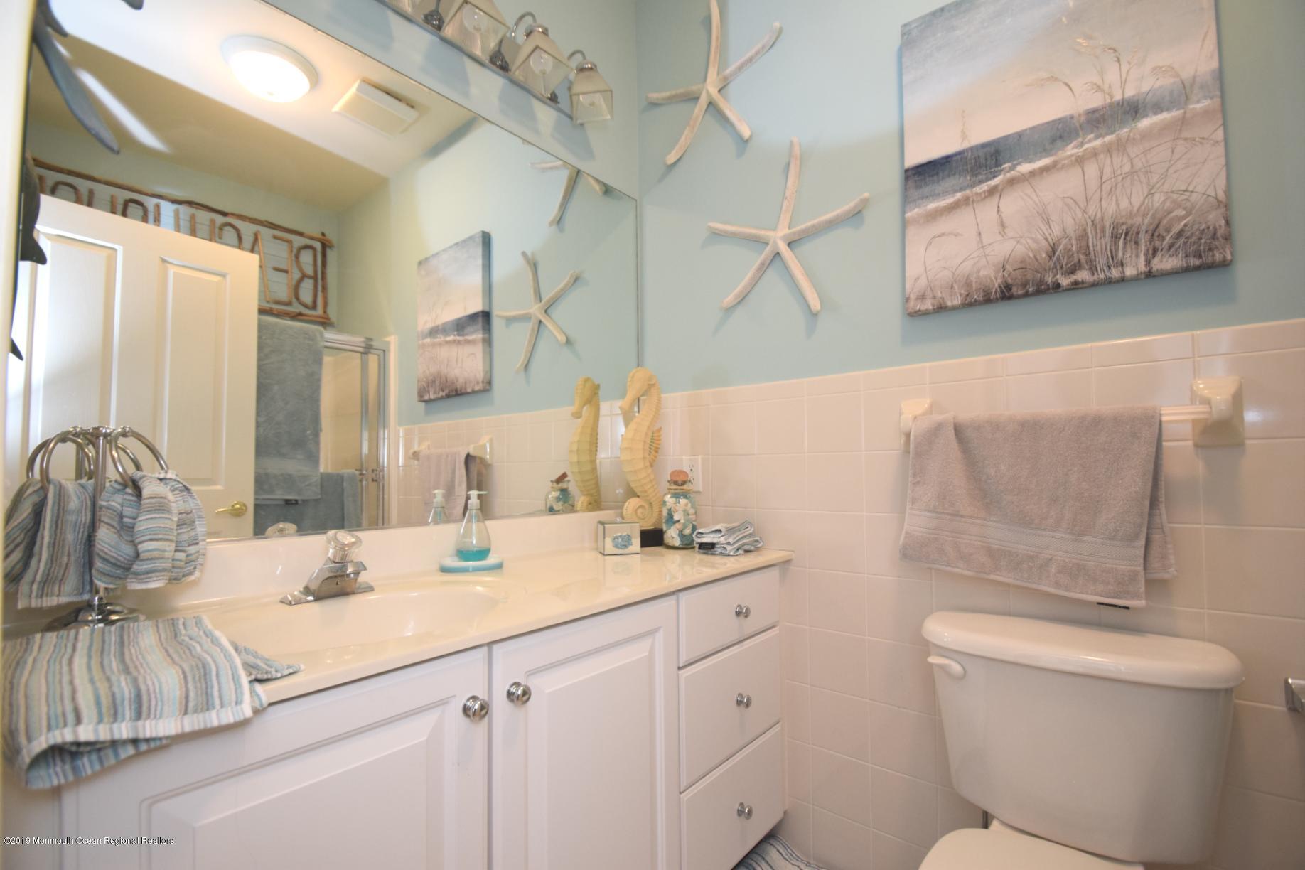 239 Beach Front, Unit 4 Manasquan, NJ 08736 - Photo 11 of 14 a bathroom with a granite countertop sink a toilet and a mirror
