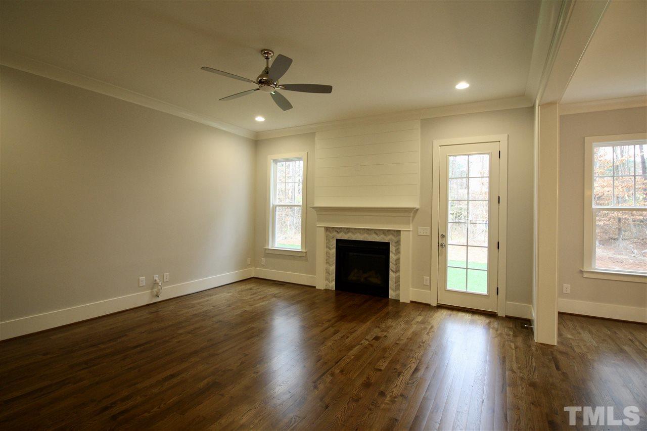 8908 Ashton Garden Way Raleigh, NC 27613 - Photo 8 of 23 an empty room with wooden floor fireplace and windows