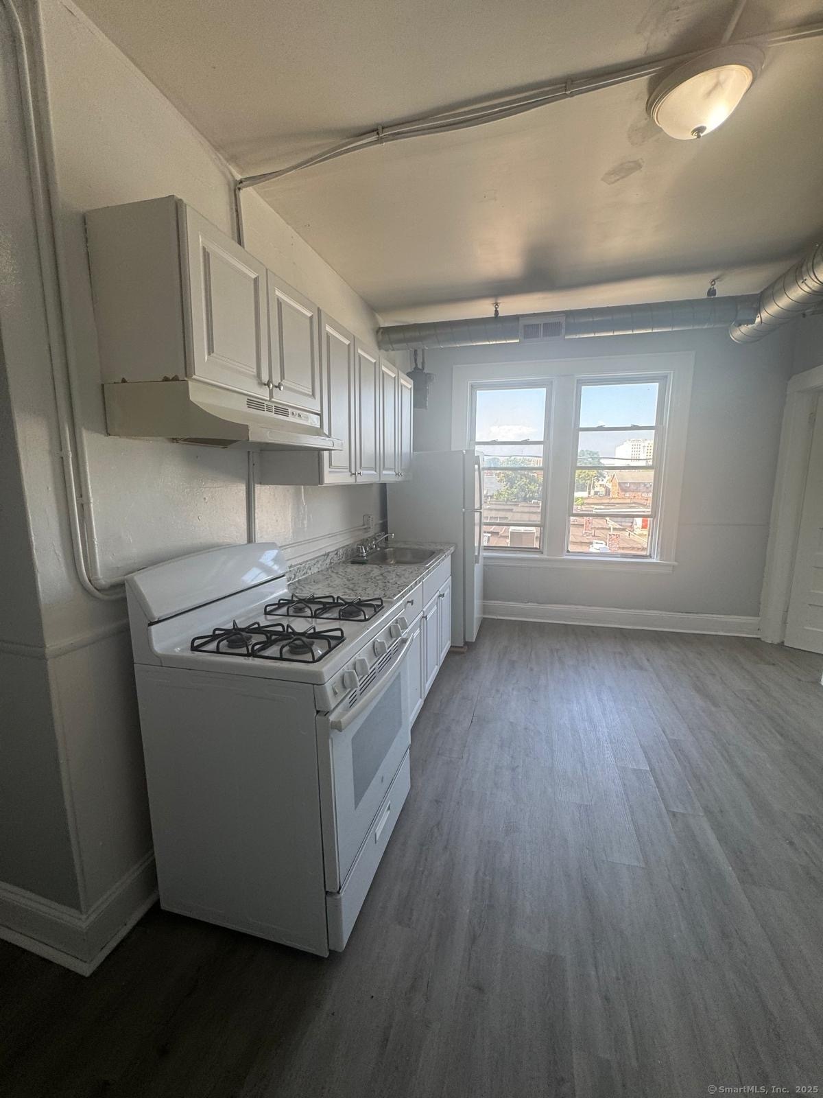 a kitchen with granite countertop a sink dishwasher a stove and a refrigerator