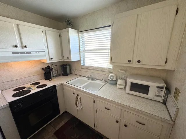 a kitchen with granite countertop white cabinets and white appliances