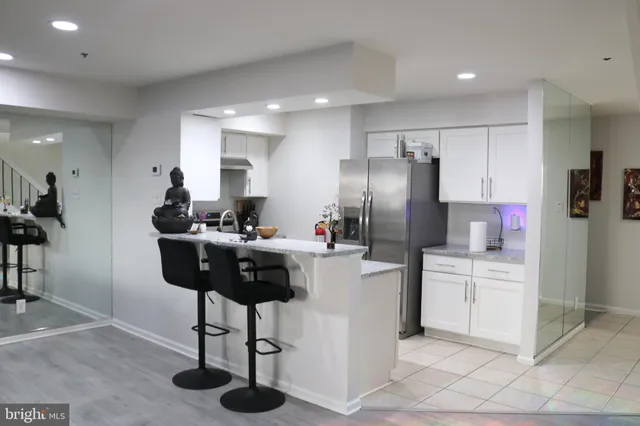 a kitchen with stainless steel appliances kitchen island granite countertop a refrigerator a sink dishwasher and a dining table with wooden floor