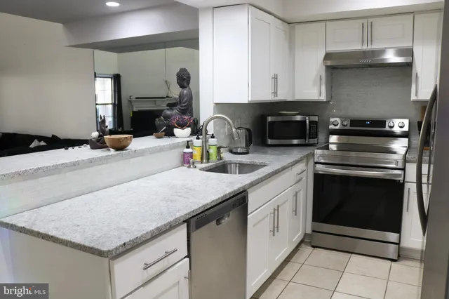 a kitchen with granite countertop a sink stainless steel appliances and white cabinets