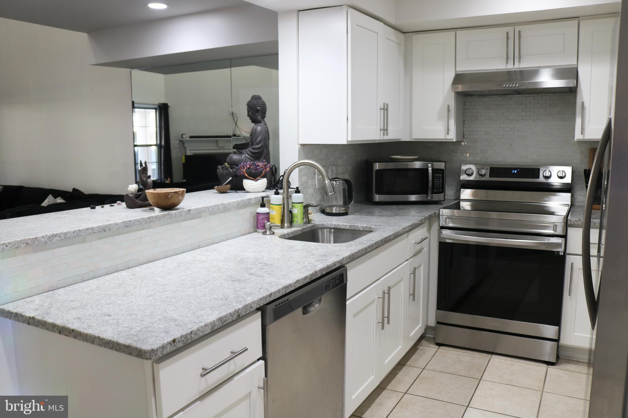 1031 Main Street Voorhees, NJ 08043 - Photo 20 of 32 a kitchen with granite countertop a sink stainless steel appliances and white cabinets