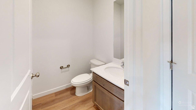 777 Pheasantbrook Drive, Unit 2B Centerville, UT 84014 - Photo 17 of 42 Powder room featuring a single vanity with an integrated sink, wood-finish flooring, and a wall-mounted mirror