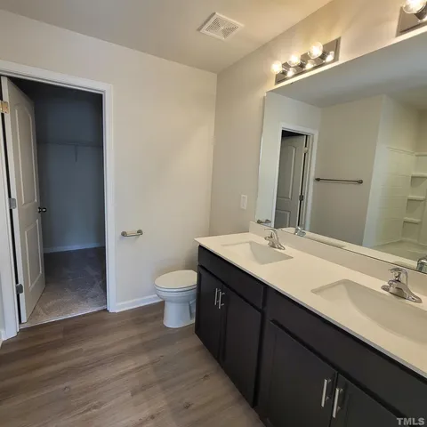a bathroom with a double vanity sink toilet and a mirror